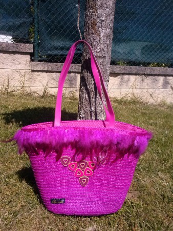2.CAPAZO ROSA. Capazo de mimbre en fucsia, con detalle de plumas y abalorios, forrado y con cierre cordón. Precio 29€.
